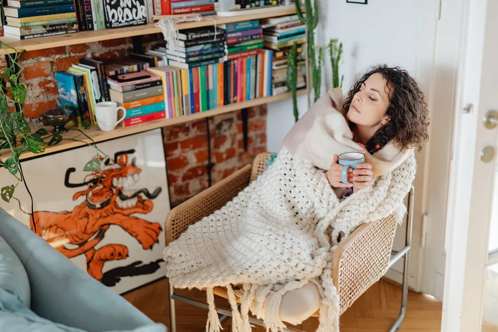 Woman wrapped in a blanket with tea after the chills that follow a night sweat